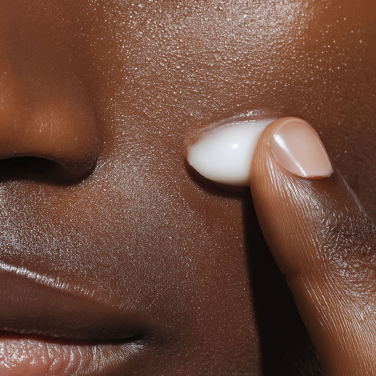 Close-up of a hand applying cream to a person's face