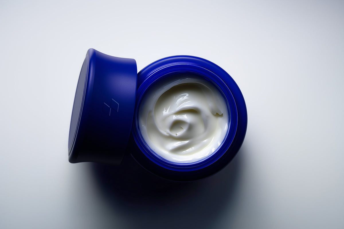 Blue jar of cream with a white cream inside on a light gray background
