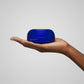 Hand holding a blue container against a light gray background