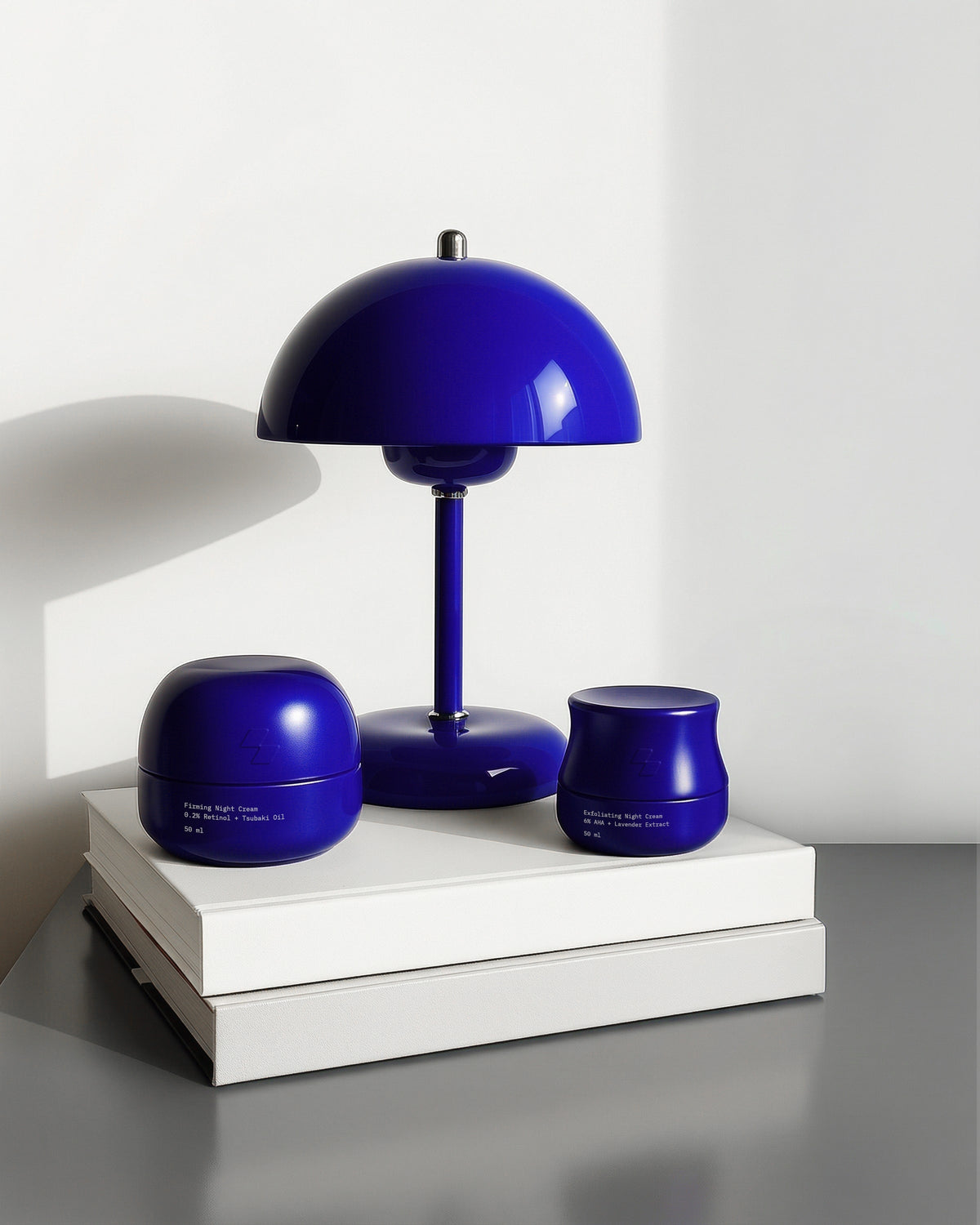 Blue table lamp and two blue containers on a white surface with a white wall background