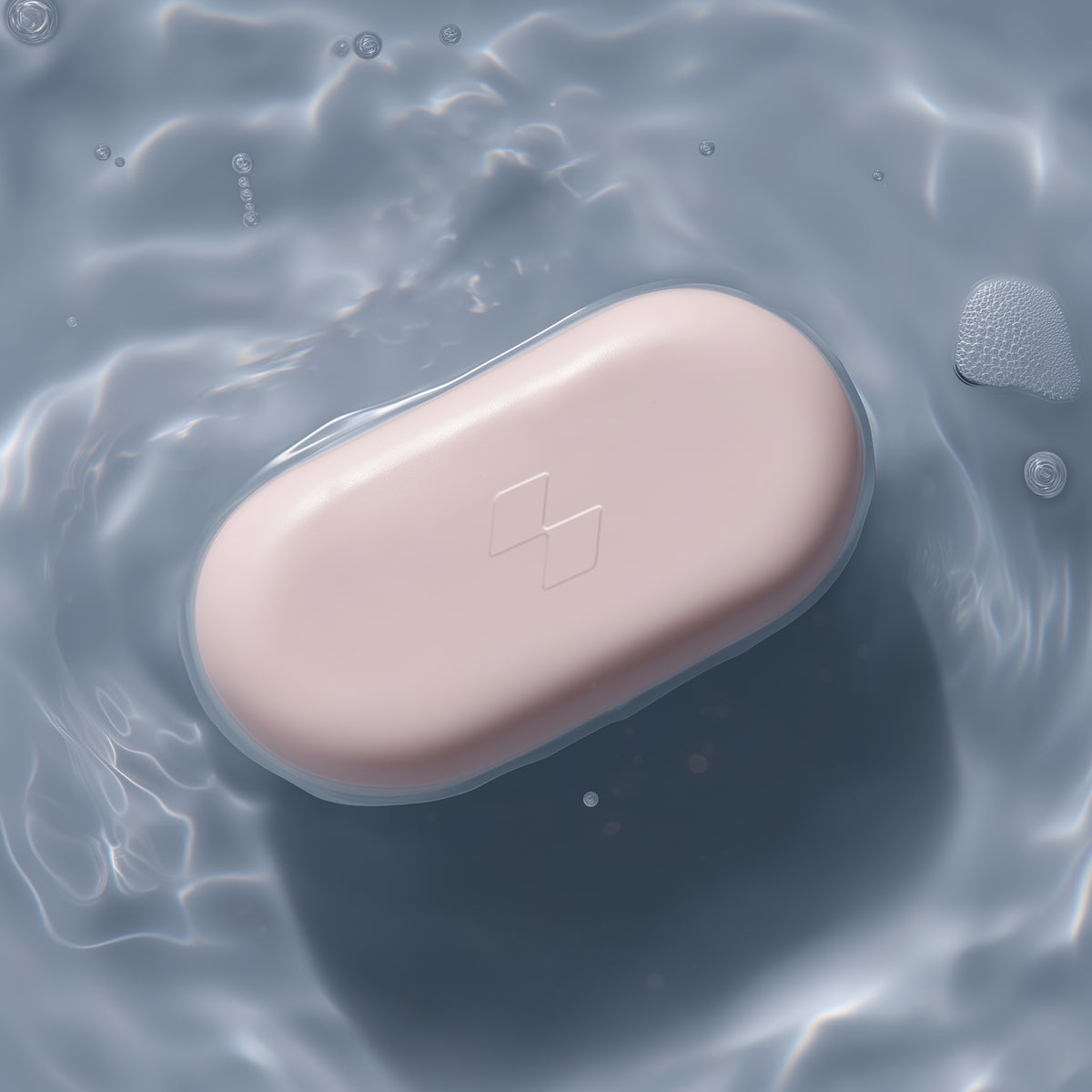 Pink soap bar floating on water with a brand logo.