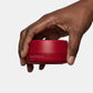 Hand holding a red container with text on a white background