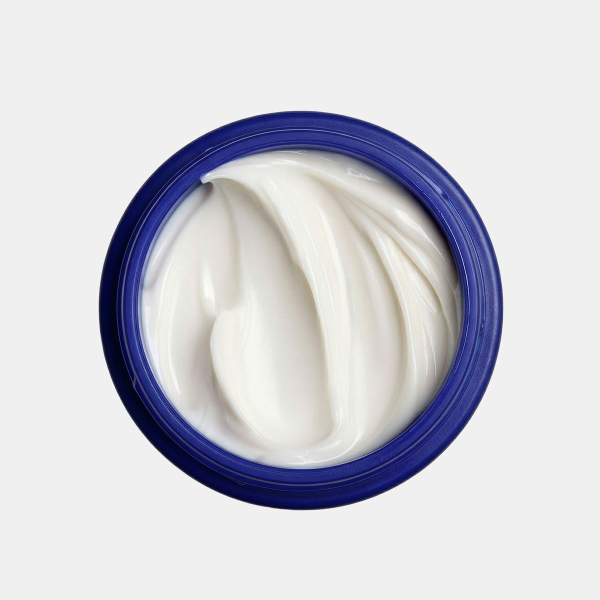 Open jar of white cream with blue lid on a light gray background