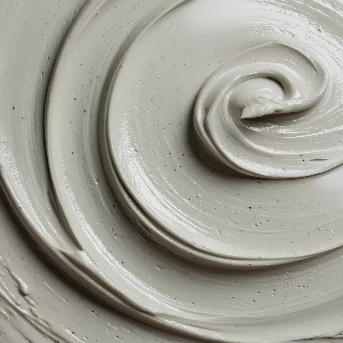 White exfoliating face mask with dark particles and swirled texture