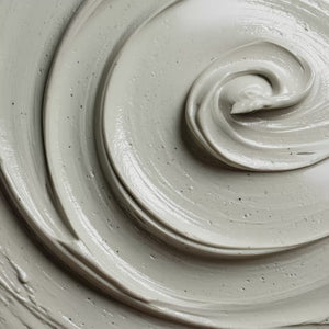White exfoliating face mask with dark particles and swirled texture