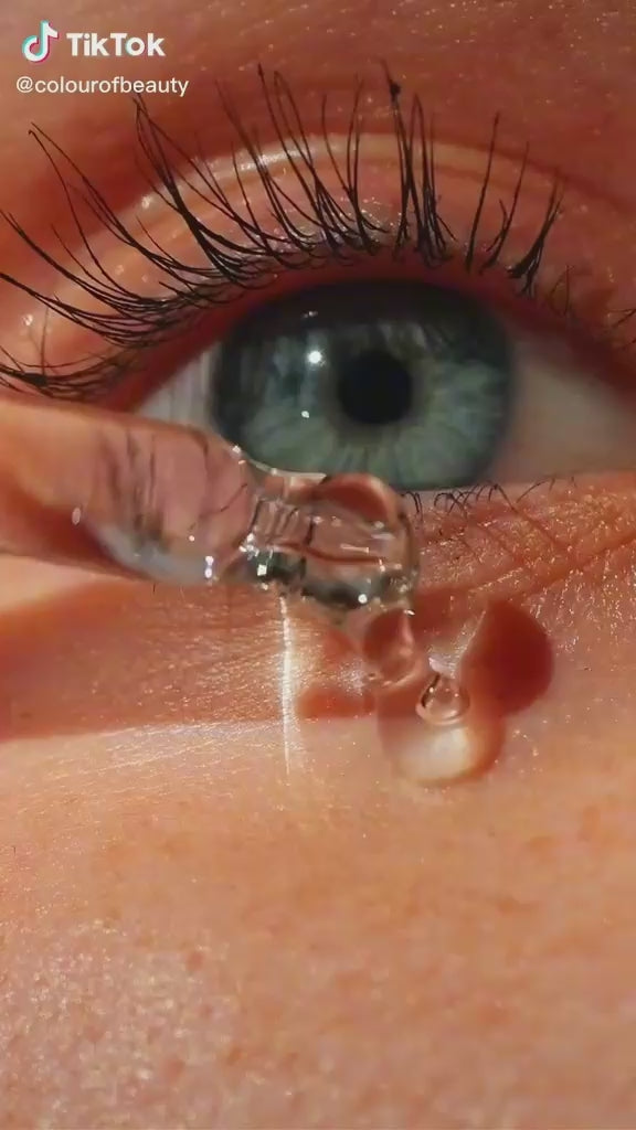 Close-up of eye with long black lashes and hydrating moisture droplets on skin