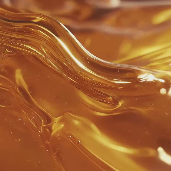 Golden skincare oil with flowing waves and shimmering amber texture