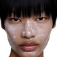 Close-up of a person with a white cream applied to their face on a white background