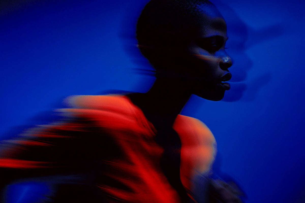 Silhouette of a person wearing a colorful garment against a blue background